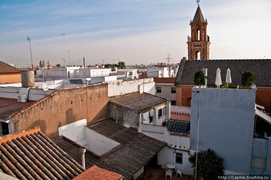 Вот такой вид открывается во время завтрака c крыши Амадеуса (крыша со сложенными зонтиками на фоне церкви с башенкой — это Ля Музика). Севилья, Испания