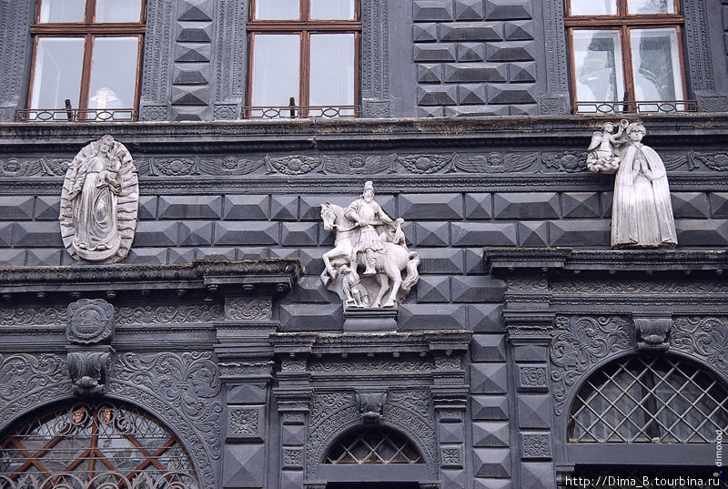 Красиво смотрится темные стены здания с белыми скульптурами на нем. Львов, Украина