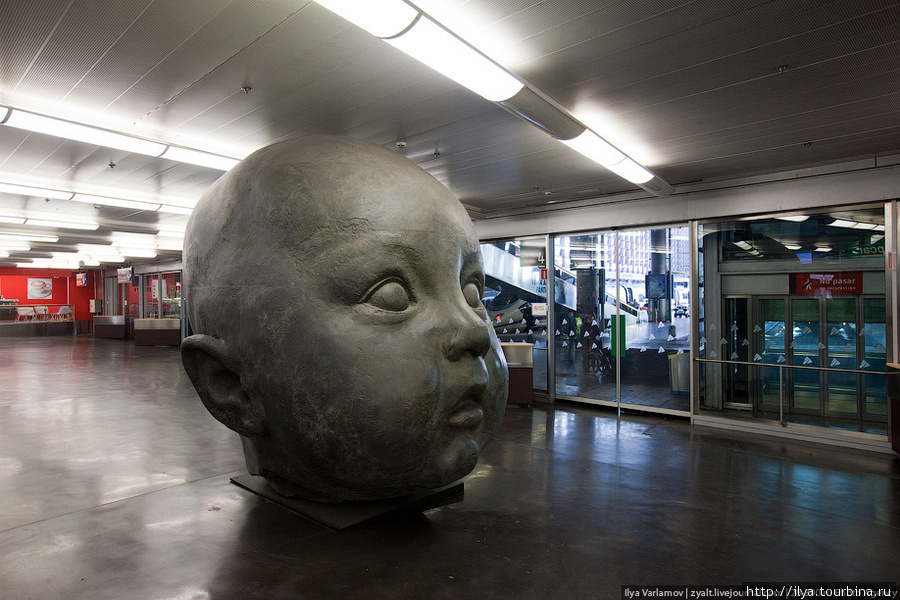 На вокзале поставили голову младенца. Еще в здании вокзала растут пальмы и ползают черепашки, а на полу можно сидеть и не испачкаться. Мадрид, Испания