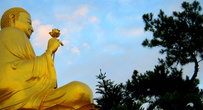 Огромный золотой Будда с цветком лотоса в руке блестел в лучах заходящего солнца