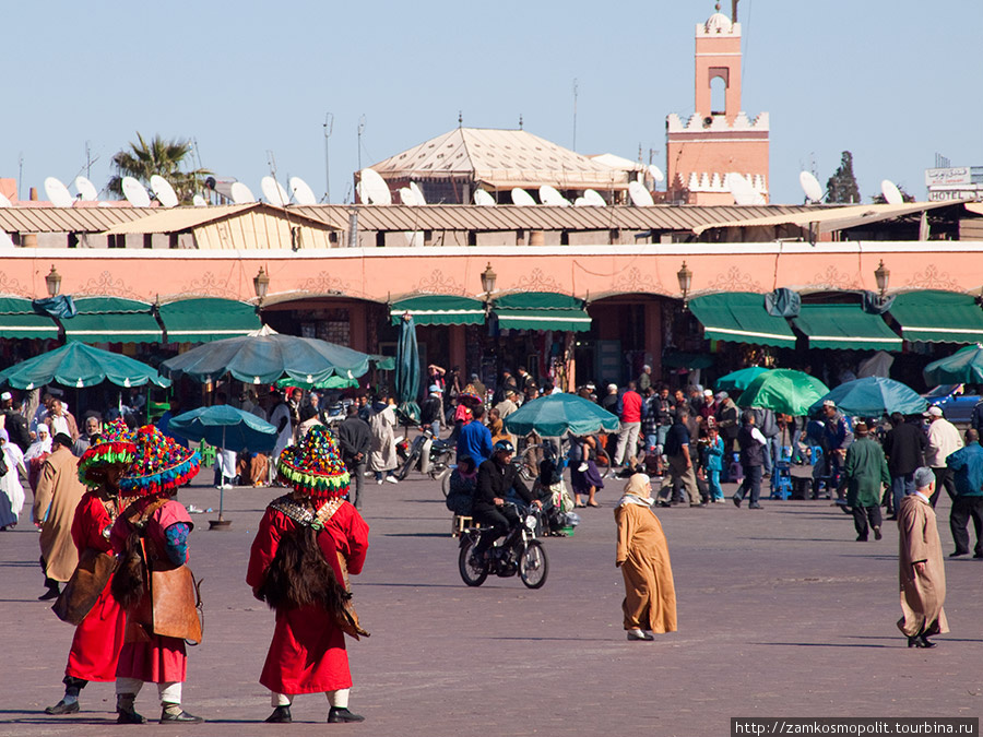 Люди в красных нарядах — это местные водоносы, такой же растиражированный и узнаваемый образ Марокко, как сама площадь. За небольшую мзду они наливают чашку воды желающим попить, нежелающих уговаривают, а туристов разводят на платные фотографии. Марракеш, Марокко