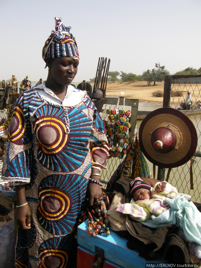 Бусы и традиционная малийская шляпа. Сзади виднеется маска бамбара (с рожками). Мали