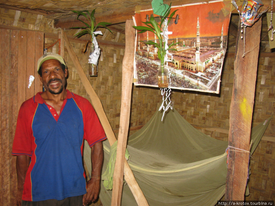 Папуас у себя в хижине, с мусульманским плакатом (на нём изображена мечеть в Медине) Папуа-Новая Гвинея