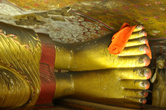 От того, как расположены ступни Будды, можно сказать, изображен ли он спящим или же достигшим Нирваны: если пальцы ног смешены (одна нога выступает), то это знак спящего — так  вехняя нога меньше давят на нижнюю.
Если же ступни ровны, Будда изображен ушедшим в Нирвану.
Оранжевое полотно — мантия буддистского монаха, наброшена в знак почтения к Учителю.