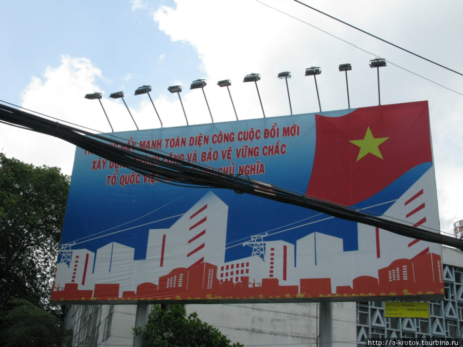 На заднем плане — плакат: светлый социализм и новые линии электропередачи, на переднем плане — электропровода Хошимин, Вьетнам