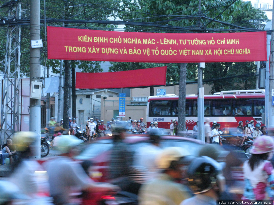 На заднем плане — плакат, что-то о Хошимине и о Ленине написано
На переднем плане — вьетнамцы на мотоциклах мчатся к светлому будущему Хошимин, Вьетнам