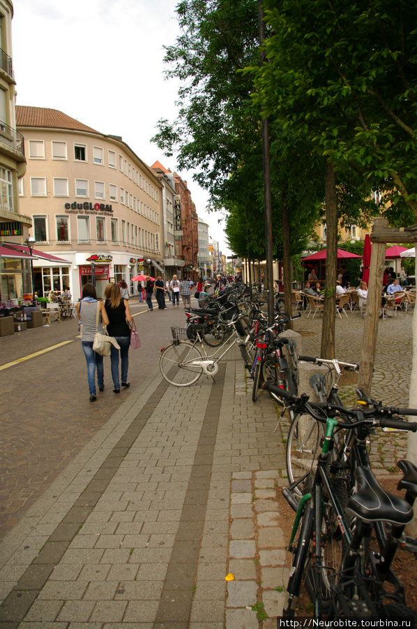 Велосипедом с фотоаппаратом через плечо по центру Карлсруэ Карлсруэ, Германия