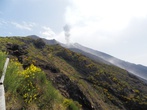 Вид на вулкан с обзорной площадки. Каждые несколько минут раздается громкое бум! и над кратером поднимается столб дыма.