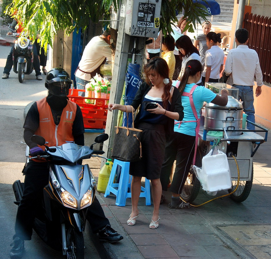 Популярный вид индивидуально-общественного транспорта. Девушка платит за проезд. Бангкок, Таиланд