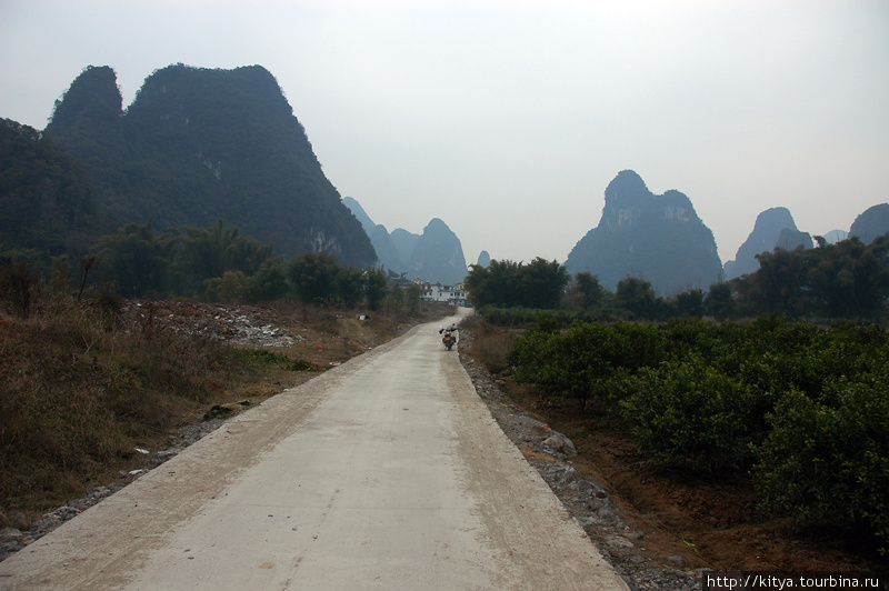 Это — деревенская дорога с покрытием. Оно кончится, когда кончится район с отелями... Яншо, Китай
