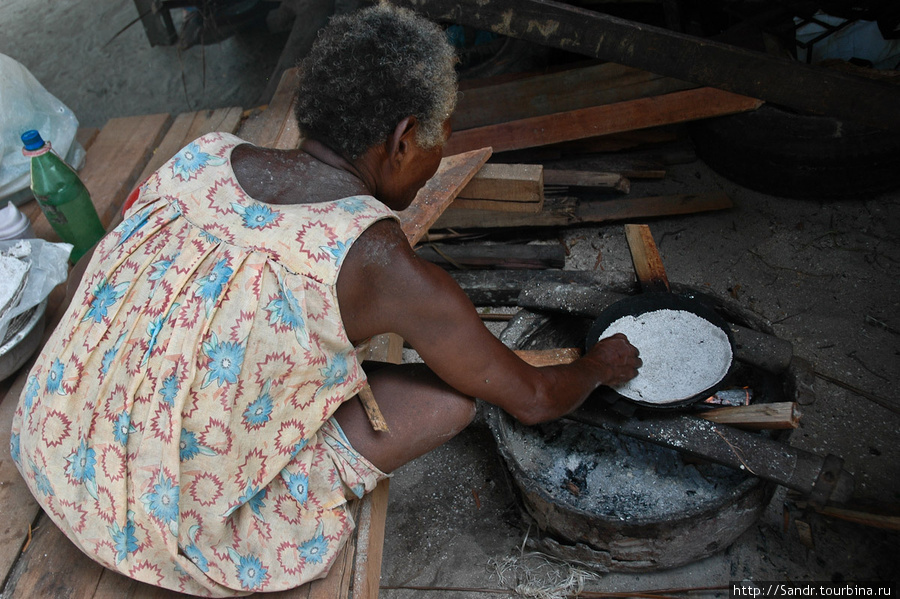 Пожилая женщина готовит СЭГО. Ингредиенты для этих лепешек добывают из стволов саговых пальм. Сэго стабильная пища в провинциях Сандаун и Восточный Сепик, но здесь в Вестдеко она не популярна. В магазинах Ванимо можно купить рис. Ванимо, Папуа-Новая Гвинея