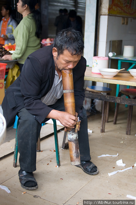 Традиционный китайский курительный прибор, что-то вроде бамбукового кальяна. С его помощью китайцы курят обычные сигареты, и делают это повсеместно, даже в автобусах. Провинция Юньнань, Китай