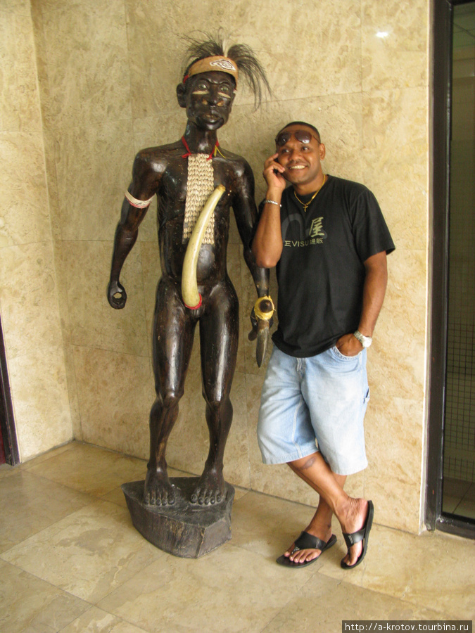 Посетитель банка (скульптура папуаса — деревянная. Стоит в фойе Банк Папуа) Джайпура, Индонезия