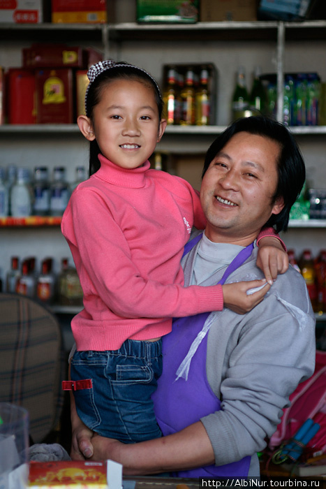 Продавец в мелком магазине с дочерью, Вейсань. Китай