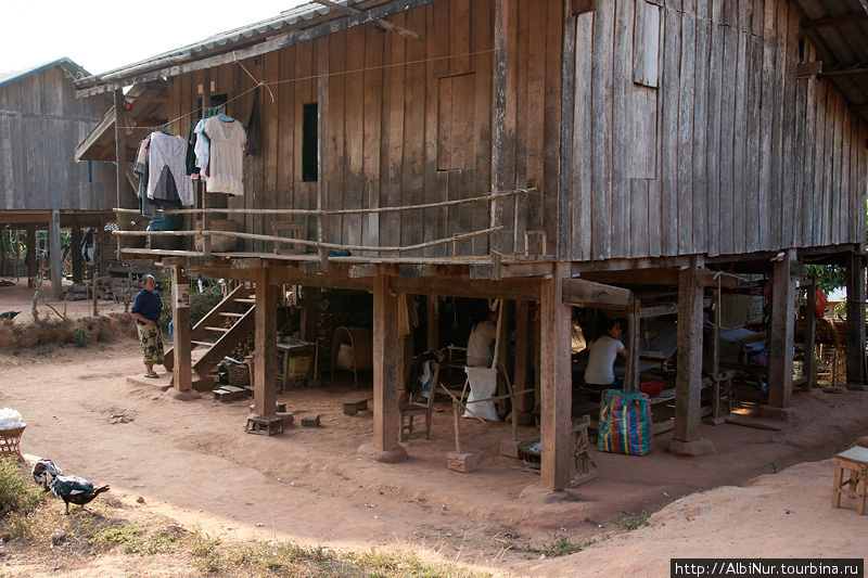 Традиционный лаосский дом на сваях. В сезон дождей это помогает сохранить дом сухим. Под домом, в тени лаосцы пережидают полуденный зной, или работают. Например здесь кустарное ткацкое производство. Сай, Лаос
