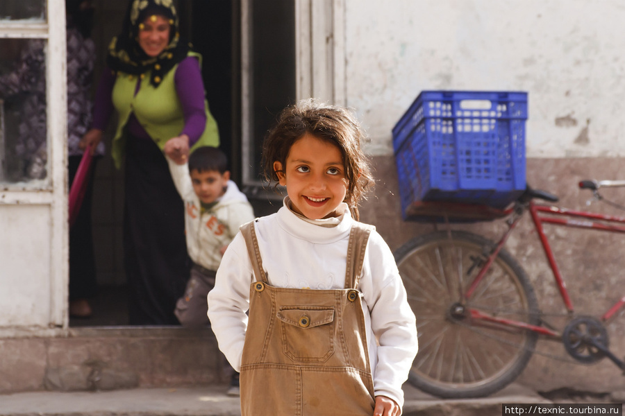Девочка позирует. Мальчик на заднем плане тащит маму на улицу, так как тоже хочет сфотографироваться Диярбакыр, Турция