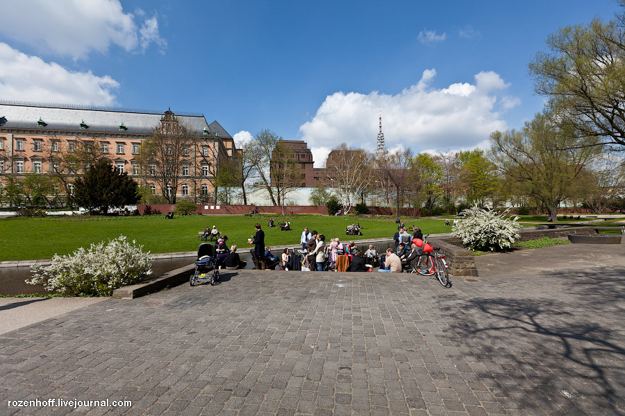 Люди устраивают пикники просто на траве. На заднем плане — городская тюрьма. Гамбург, Германия