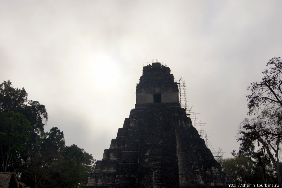 Солнце пробивается сквозь утренние облака Тикаль Национальный Парк, Гватемала
