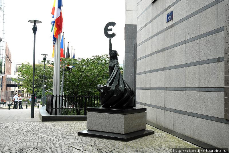У здания ЕвроПарламента памятник-скульптура знаку Евро. Брюссель, Бельгия