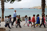 Дети из детсада прогуливаются вдоль моря, и хором повторяют стихи своему воспитателю.