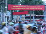 На заднем плане — плакат, что-то о Хошимине и о Ленине написано
На переднем плане — вьетнамцы на мотоциклах мчатся к светлому будущему