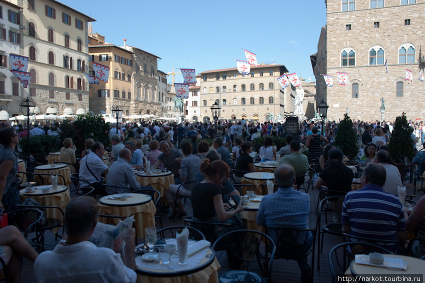в кафе на площади Синьёрии, впереди знаменосцы подбрасывают флаги. Флоренция, Италия
